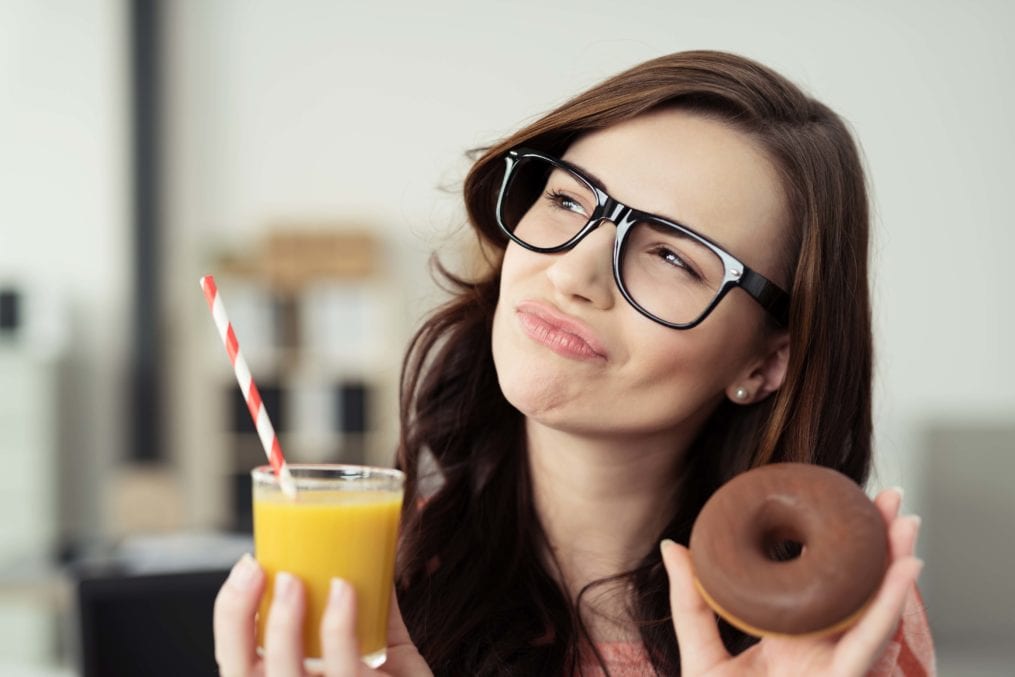 woman holding doughnut and juice drink